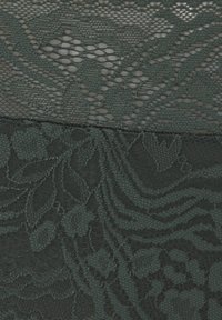 Donkergroene kantstof met ingewikkelde bloempatronen en een gestructureerd ontwerp. Het materiaal is semi-transparant met gelaagde details.