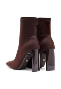 Bottines en satin marron avec un talon noir brillant, fermeture éclair et design à bout pointu. Présente des coutures discrètes et un accent décoratif.