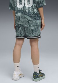 Mint green sports outfit featuring snake skin pattern, short sleeves, and matching shorts. White sneakers with gold accents and white socks.