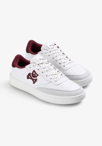 Baskets en cuir blanc avec une accent maron au col, arborant un logo de skull et os croisés, un bout perforé et une semelle texturée.