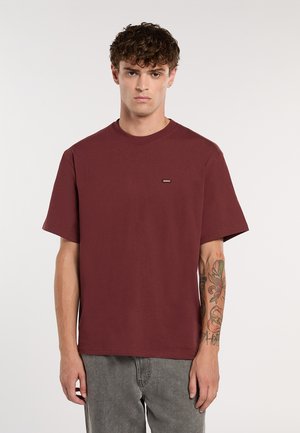 Burgundy bomulds t-shirt med rund hals og korte ærmer. Har et lille logo på brystet og en afslappet pasform.