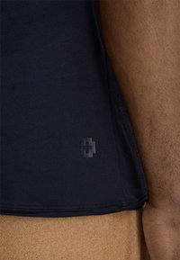 T-shirt in cotone navy con un logo testurizzato discreto vicino all'orlo, con scollatura arrotondata e maniche corte. Tessuto con una finitura liscia.