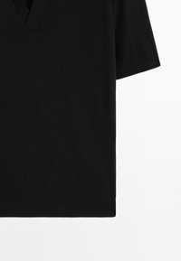 Top corto a maniche corte nero lavorato a maglia con scollo a V, caratterizzato da un tessuto testurizzato e orlo a coste, presentato su uno sfondo bianco puro.