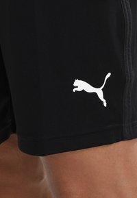 Schwarze Sportshorts aus Stretchstoff mit einem weißen, springenden Puma-Logo auf der unteren linken Seite und kontrastierenden Seitennähten.