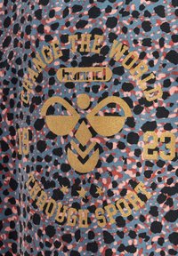 Mönstrad tyg i blått, rosa och svart med guldtext och accenter. Innehåller "Change the World" samt sportrelaterade logotyper och nummer.