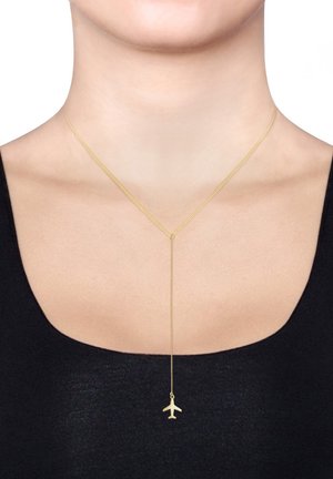 Collier doré avec une fine chaîne et un pendentif en forme d'avion, présentant une texture lisse et un design minimaliste, porté sur un haut noir.