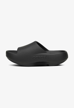 Schwarze Slip-On Slide-Sandale mit dicker gepolsterter Sohle und offenem Zehenbereich, mit geschwungenem ergonomischem Design und "Oofos"-Logo an der Seite.