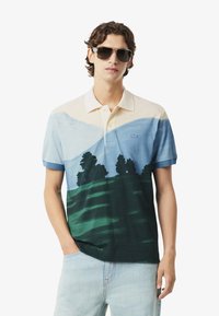 Pikepaita sinisen, kermaisen ja vihreän sävyissä, jossa on maisemakuva vuorista ja puista. Lyhyet hihat ja klassinen kaulustyyli.