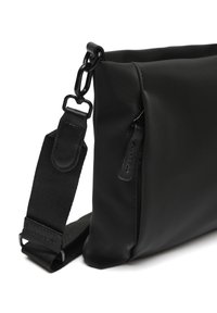 Borsa in nylon nera con una texture liscia, dotata di una tasca con zip e di una tracolla regolabile. Gli accessori includono un gancio in metallo e dettagli in pelle.