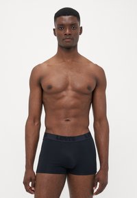Black boxer briefs made of soft material, featuring a waistband with the "Levi's" logo, fitted design, and mid-thigh length.