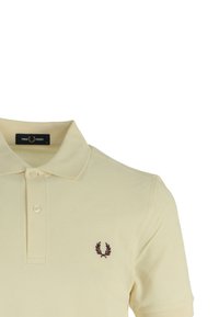 Polo giallo realizzato in tessuto testurizzato, con chiusura a due bottoni e logo ricamato sul petto in rosso scuro.
