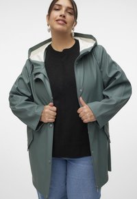 Green waterproof rain jacket with a hood, featuring a zip and snap button closure, prominent pockets, and a smooth glossy texture.