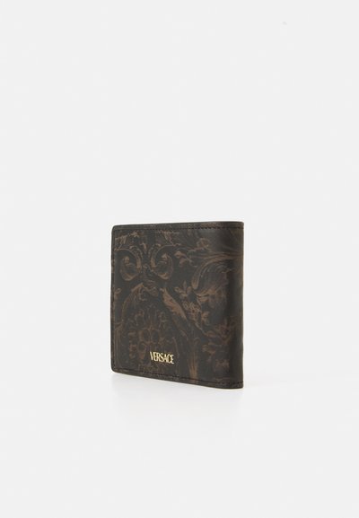 Melna ādas maka ar iegravētu ziedu rakstu, kurā ir redzams zeltains "Versace" logo akcenti un salocīts dizains.