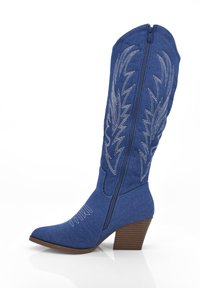 Bota de denim azul hasta la rodilla con punta afilada y un tacón texturizado marrón; presenta patrones florales bordados en plata y una cremallera lateral.