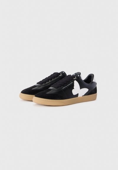 Un paio di sneakers nere con suole in gomma, lacci neri, logo di una farfalla bianca sui lati e testo del marchio sul bordo esterno, su sfondo bianco.