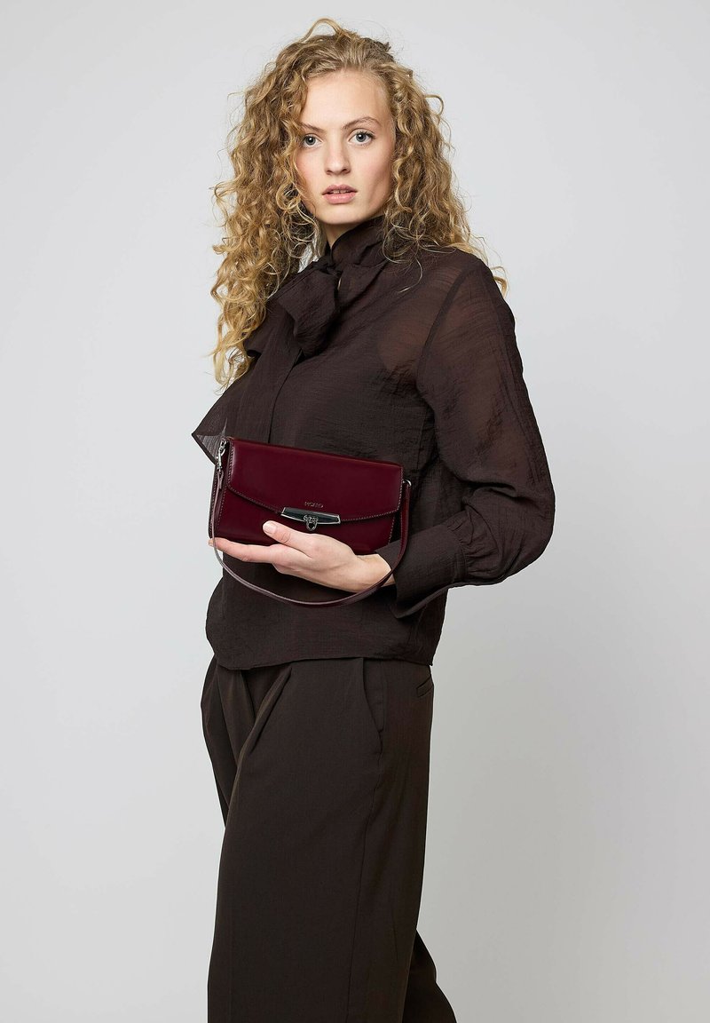 Bordeauxrote Lederhandtasche mit silberner Schnalle und abnehmbarem Tragegurt, mit schlanker, rechteckiger Form und glatter Textur.