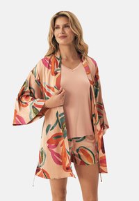 Różowa, zielona i pomarańczowa szlafrok w stylu kimono z wyrazistymi kwiatowymi wzorami, zestawiony z gładkim różowym topem z dekoltem w serek i dopasowanymi szortami. Satynowa faktura.