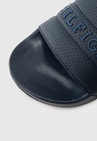 Σκούρο μπλε σαγιονάρα με διάτρητο λουράκι, υφασμένο πέλμα και ανάγλυφο λογότυπο. Λ�επτή ελαστική σόλα και εργονομικό σχήμα για άνεση.