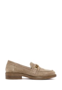 Mocasines de ante beige con un tacón bajo y cuadrado, que presentan un motivo metálico dorado en una correa y detalles de costura a lo largo de los bordes.