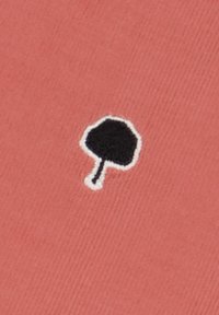 Roze stof met een geribbelde textuur, met een klein zwart geborduurd paddenstoelenontwerp omlijst in het wit.