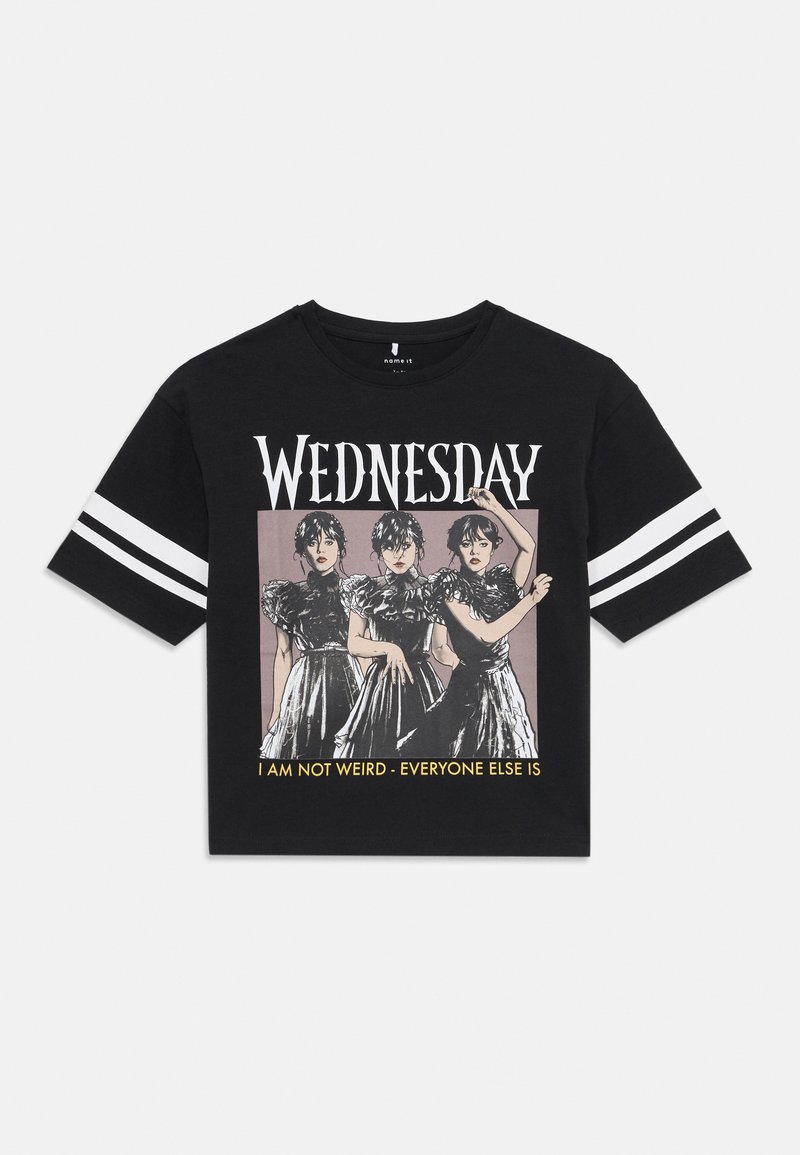 Melnā īsām piedurkņu T-kreklā ir attēloti trīs varoņi melnās kleitās. Texts saka "TREŠDIENA" un "ES NEESMU DĪVAINA - VISI PĀRĒJIE IR".