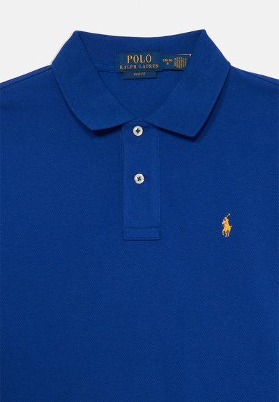 Camiseta polo azul con una tela texturizada, tapeta de tres botones y un logo bordado amarillo en el lado izquierdo del pecho. Diseño ajustado.