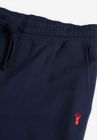 Marineblauwe sweatpants van zachte katoen, met een elastische tailleband met trekkoord en een klein rood geborduurd kreeftenlogo op het onderbeen.