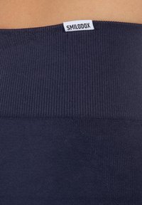 Navyblauwe ribband met een gladde textuur en een klein wit "SMILODOX" label aan de bovenkant. De stof lijkt rekbaar en functioneel.