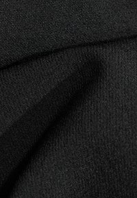 Tissu noir avec une surface texturée, présentant une finition lisse et un léger éclat, montrant des plis et un bord net.