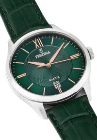 Reloj de cuarzo verde con esfera texturizada, caja plateada y agujas en oro rosa. Presenta una correa de cuero verde oscuro y un indicador de fecha a las 6 en punto.