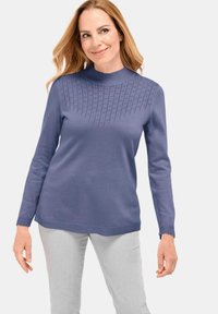 Pull à manches longues en doux violet clair avec un col montant. Présente un design tricoté texturé au niveau de la poitrine et un ourlet droit.