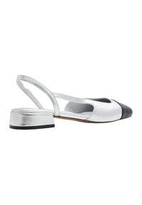 Zapato slingback plateado con punta redondeada, acabado metálico y una puntera negra en contraste. Cuenta con un tacón bajo en bloque y un diseño con recortes.