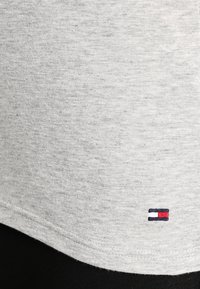 Gray cotton t-shirt with a soft texture, featuring a small embroidered logo in red, white, and blue at the bottom left corner.