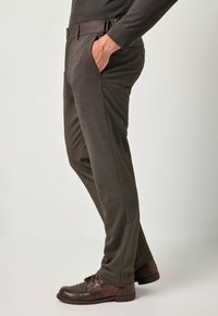 Donkerbruine, textuur van stof, broek met zijzakken, elastische tailleband en getailleerde pasvorm, gecombineerd met donkerbruine veterschoenen.