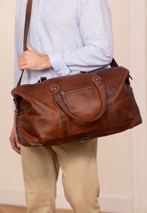 Braune Leder-Reisetasche mit glatter Textur, zwei Griffen, verstellbarem Schultergurt und einer Vorderreißverschlusstasche.