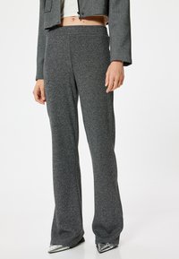 Pantalones grises texturizados de tiro alto con un diseño de pernera ancha. La tela tiene un suave brillo y una cinturilla elástica y suave.