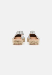 Scarpe slip-on metallizzate argento con apertura sul retro, suole a piattaforma intrecciate in juta e una texture liscia per comfort e stile.