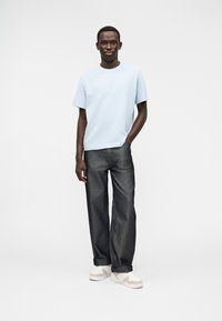 Hele sinine puuvillane lühikeste varrukatega t-särk, kombineeritud tume teksapükste ning valgete sametiste tennistega, millel on beežid aktsendid. Lihtne, vabaaja riietus.