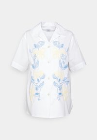 Camicetta bianca a maniche corte con ricamo floreale blu e giallo, chiusura a bottoni e colletto classico. Tessuto liscio e leggero.