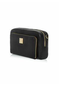 Czarna skórzana torba z złotymi zamkami błyskawicznymi, prostokątny kształt, przednia kieszeń i mała złota tabliczka z logo. Gładka tekstura, minimalistyczny design.