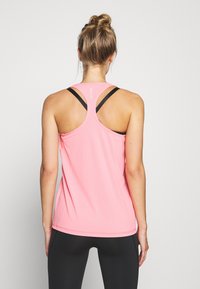 Top deportivo rosa con diseño de espalda nadadora, que presenta acentos negros y una textura suave y transpirable; perfecto para el uso activo.