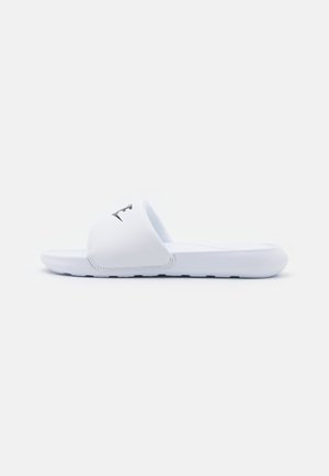 White slide sandals with a smooth synthetic upper, open toe design, and textured footbed. Features a black logo on the strap.