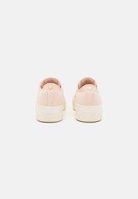 Růžové plátěné tenisky s texturovaným povrchem, s bílou gumovou podrážkou a zlatou hvězdou na patě.