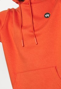 Orange hoodie med kängurufickor, dragsko på huven med orangea toppar och en liten svart logotyp på bröstet.