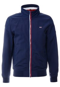 Marineblaue Jacke mit hohem Kragen, Vorderreißverschluss und roten und weißen Akzenten. Verfügt über Seitentaschen sowie gerippte Bündchen und Saum.