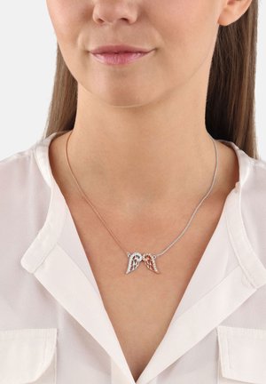 Collana con due pendenti a forma di ali, uno in argento e uno in oro rosa, impreziositi da scintillanti dettagli. Indossata su una delicata catena sopra una camicetta.