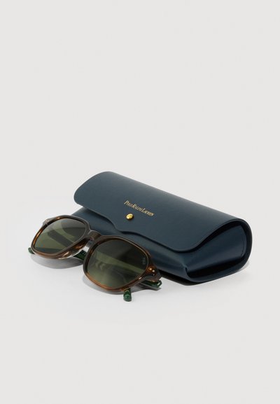 Ochelari de soare din scoică de țestoasă cu lentile verde închis, așezați lângă o carcasă închisă de culoare albastru marin de la Polo Ralph Lauren, cu un buton auriu.