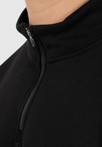 Zwarte longsleeve pullover met hoge kraag en ritsluiting. Glad materiaal met verstevigde naden en een minimalistisch design.