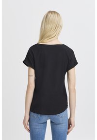 T-shirt nera a maniche corte con scollo rotondo, vestibilità rilassata e polsini arrotolati. Tessuto di cotone liscio con una texture morbida.