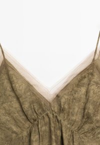 Olive green dress featuring a v-neck design, gathered waist, and layered sheer straps with a subtle textured pattern.